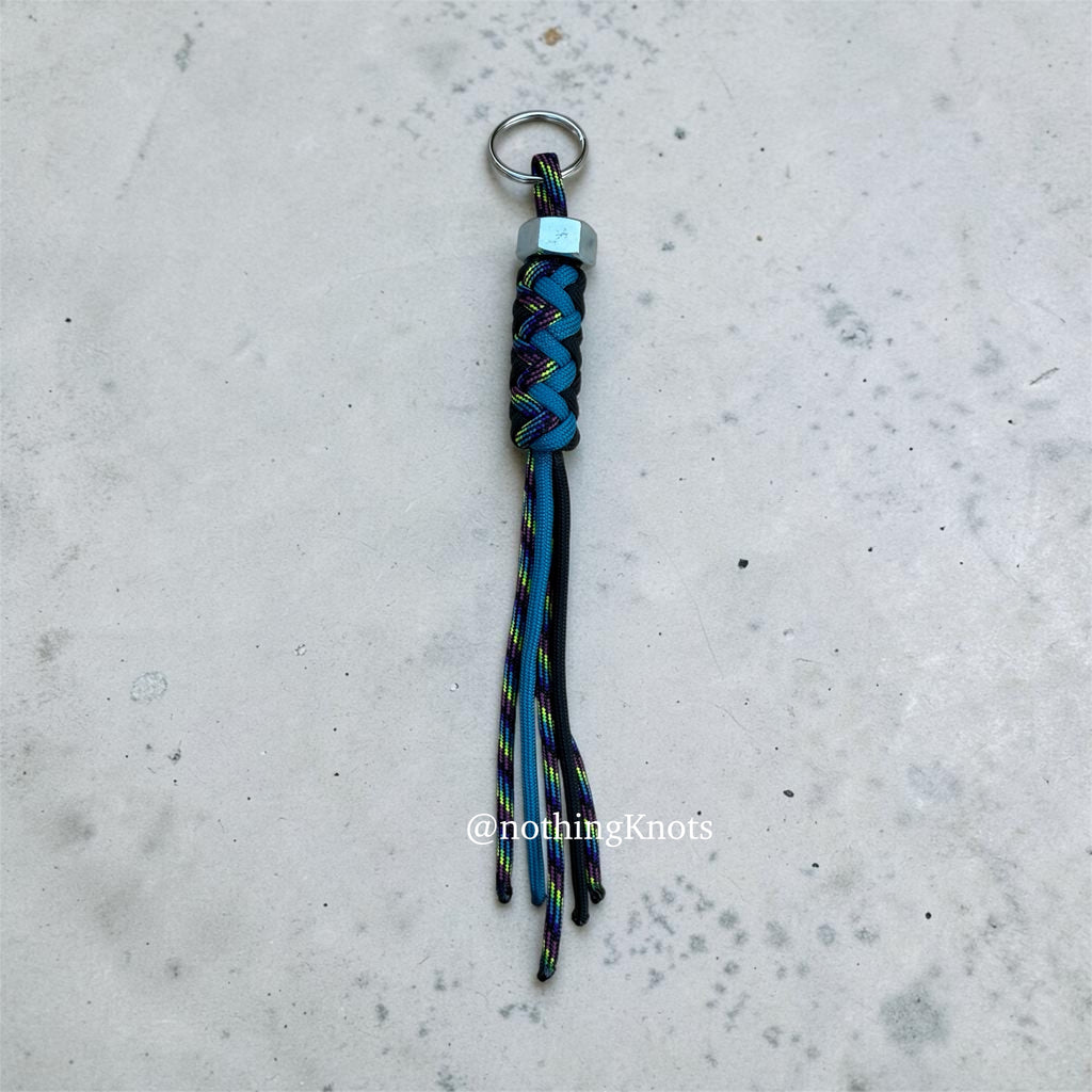 Paracord Decorative Keychain in Black, Blue, and Dark Rainbow on a split ring with hex nut