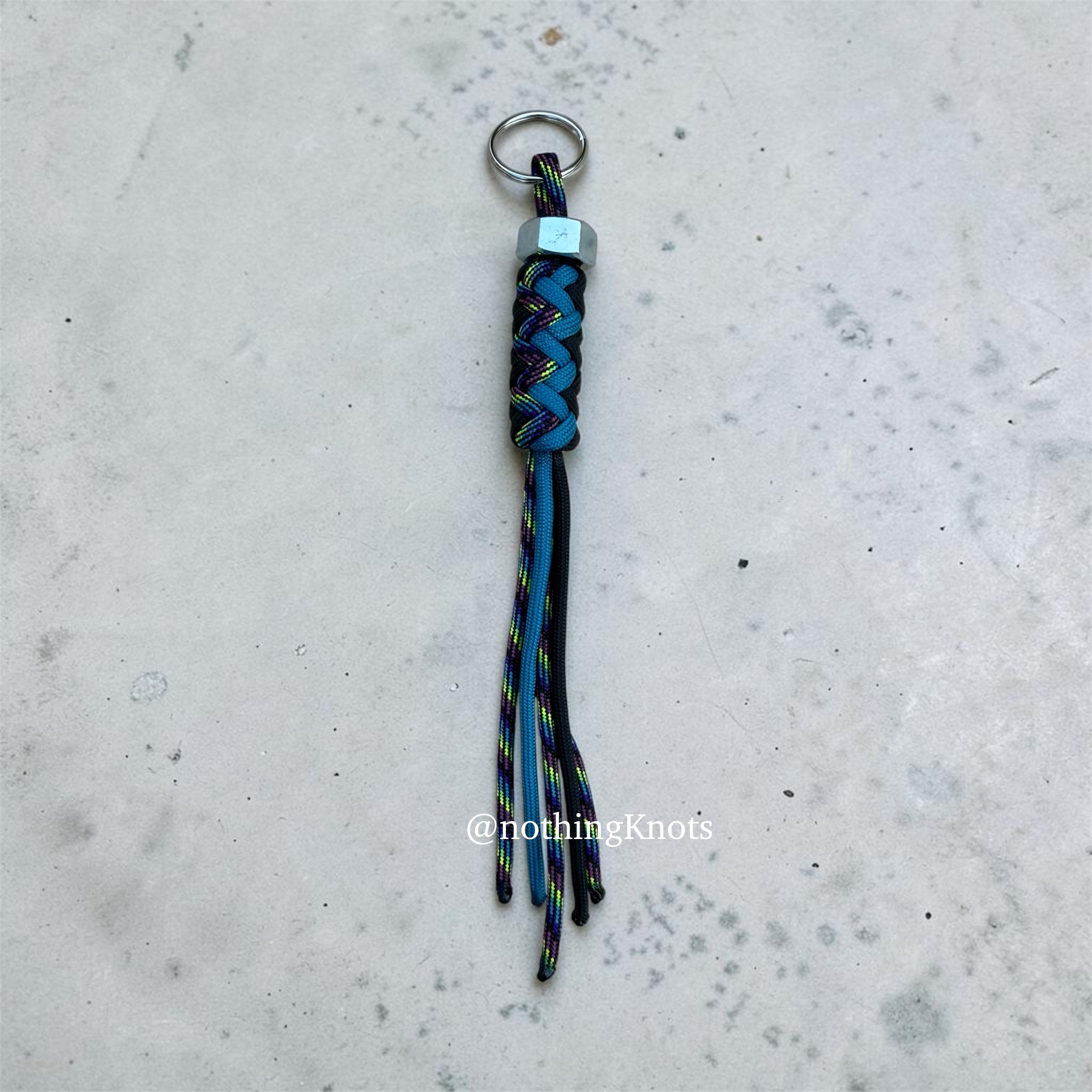 Paracord Decorative Keychain in Black, Blue, and Dark Rainbow on a split ring with hex nut